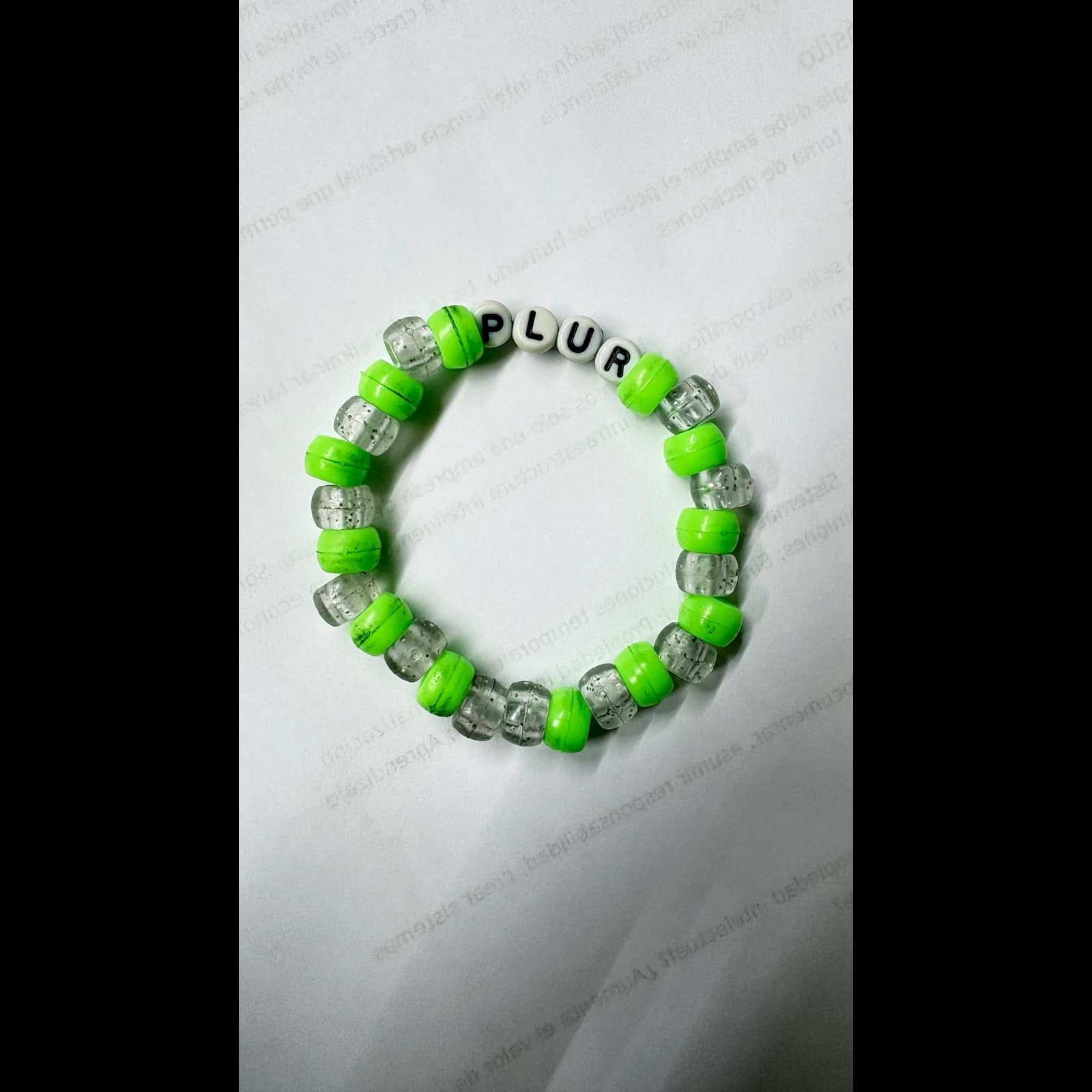 Handmade stretch bracelet with neon green and clear beads and letter beads spelling PLUR